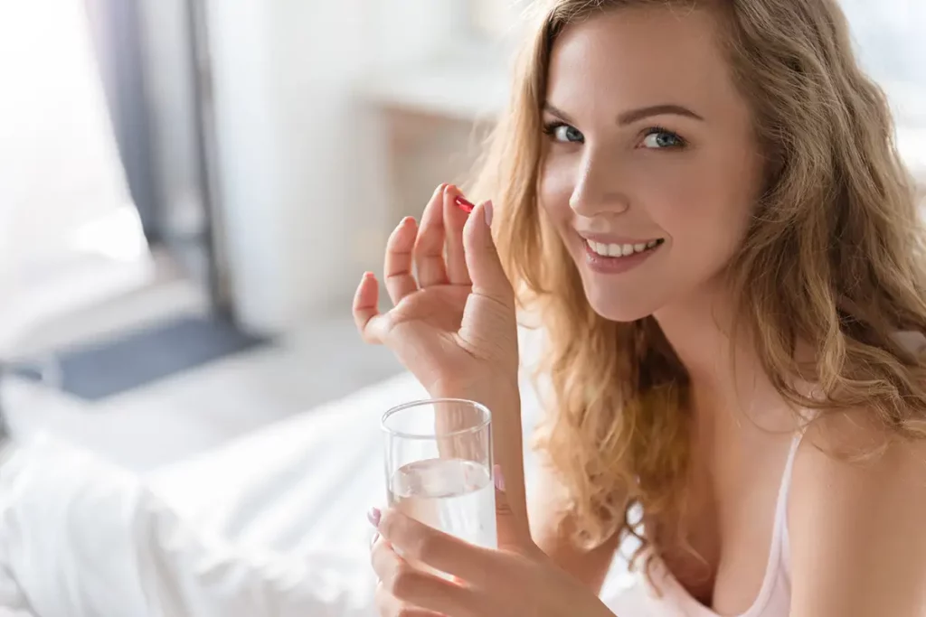 smiling young woman taking a hormone therapy pill